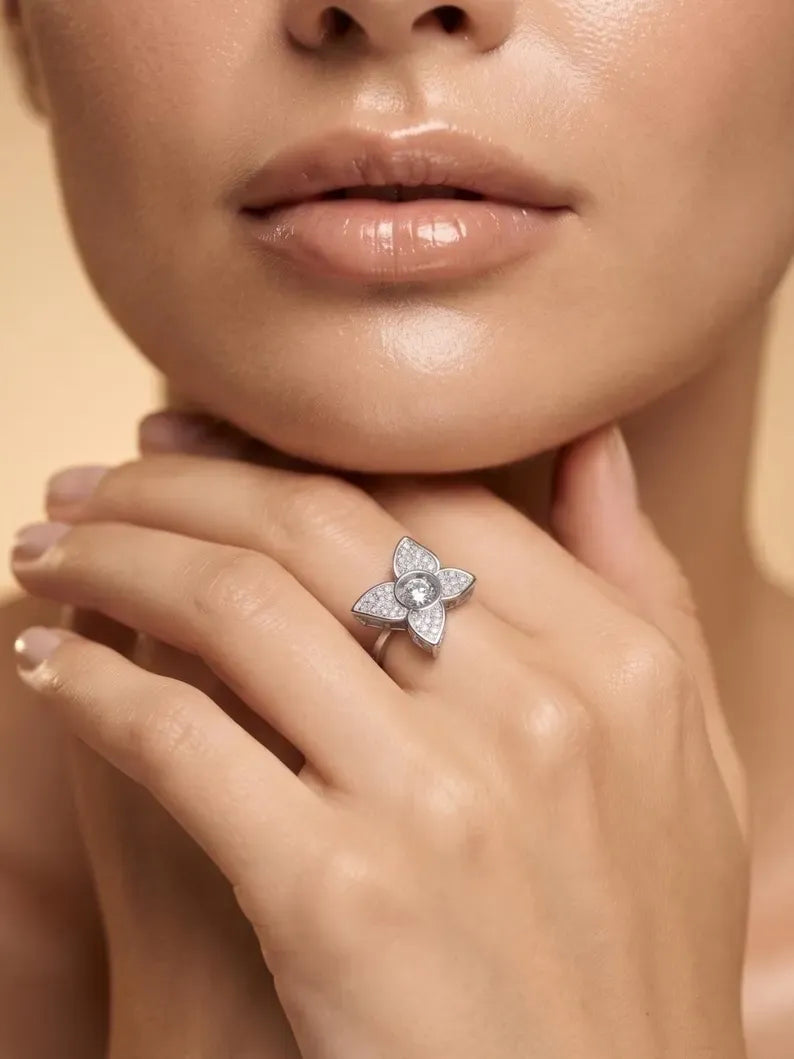 Woman wearing a 925 sterling silver four-petal flower ring with a round CZ center, hand resting under her chin