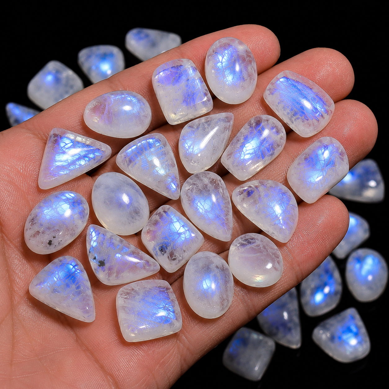 Hand holding a collection of faceted gemstones with a dark background
