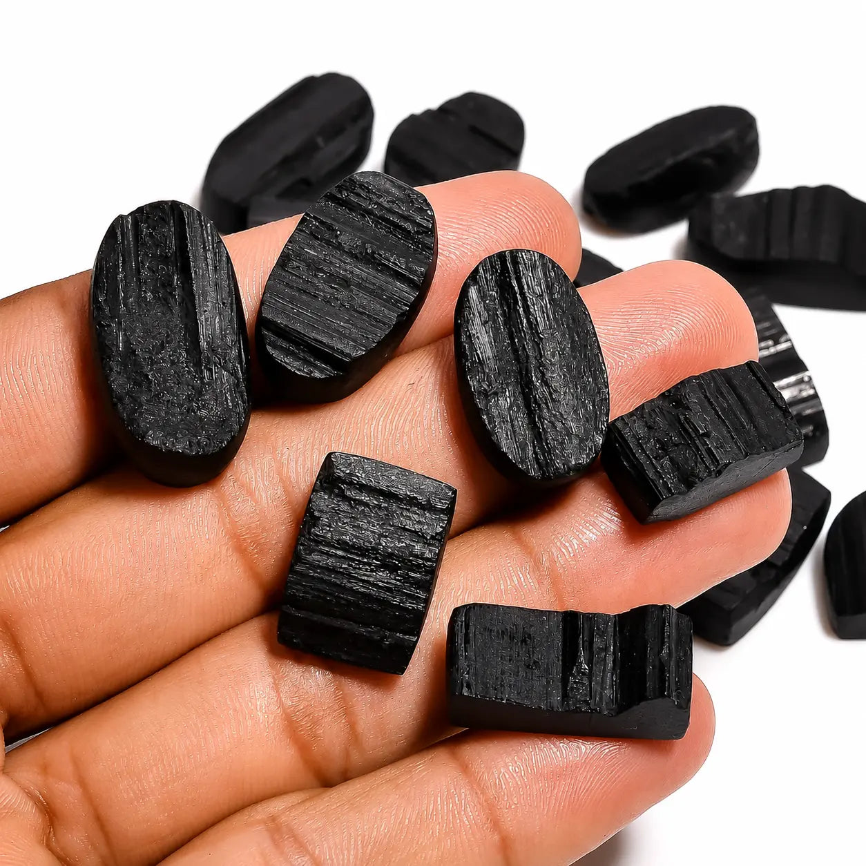 Hand holding black stones with a white background