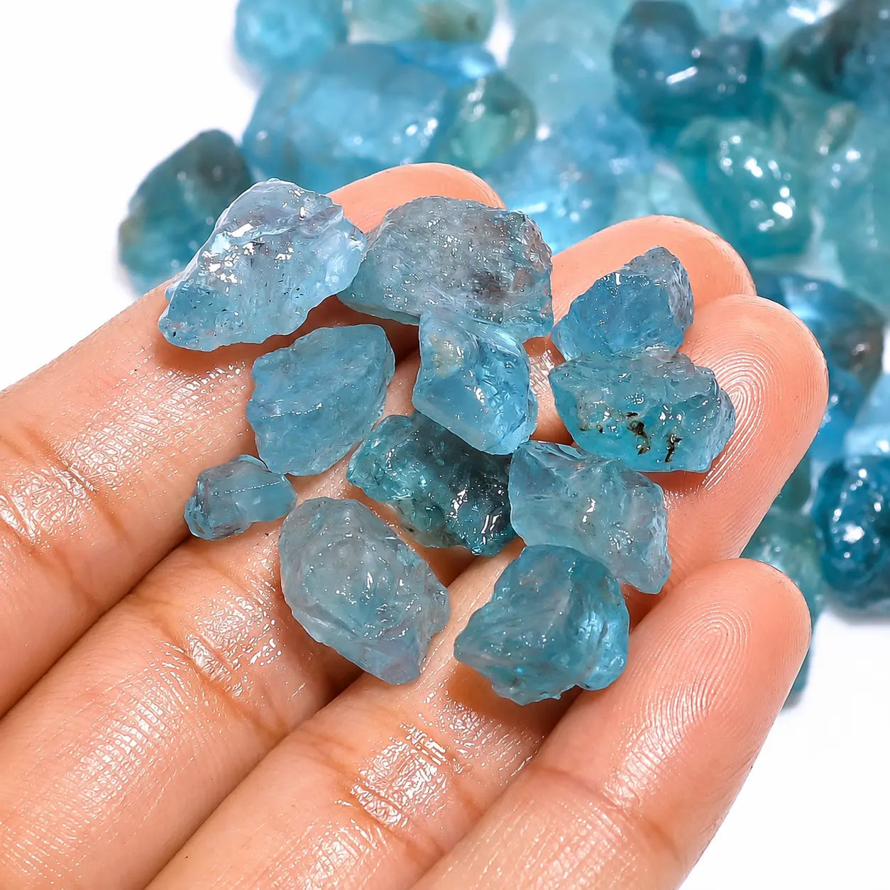 Hand holding blue crystal rocks with a close-up background of more crystals.