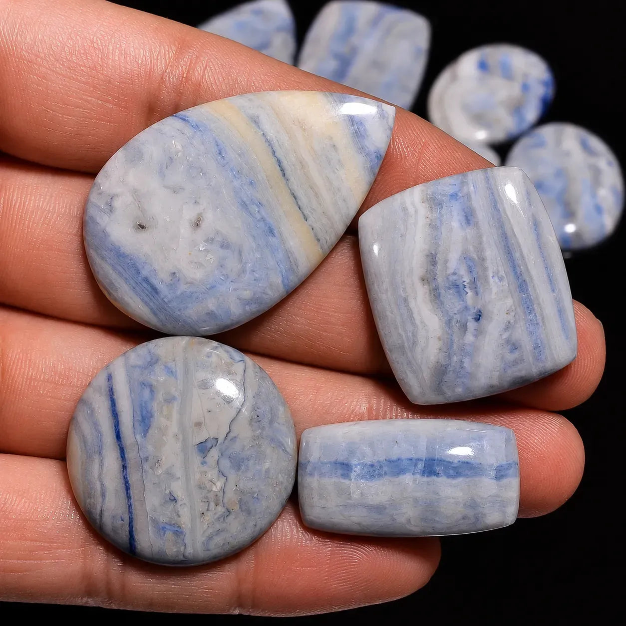 Blue and white marbled stones held in a hand with a dark background