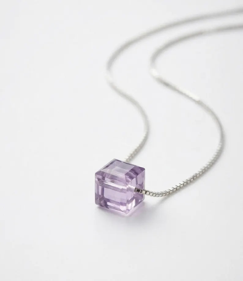 A silver chain necklace featuring a faceted, cube-shaped lavender purple gemstone pendant, photographed on a clean white background.