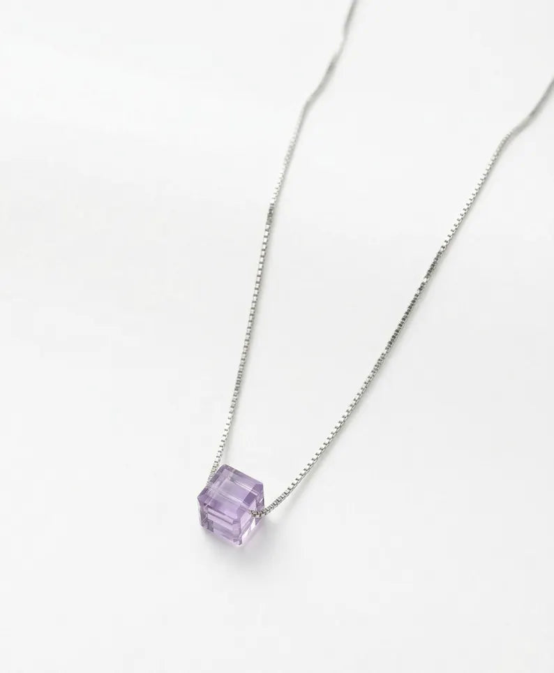 A silver chain necklace with a faceted purple cube pendant, photographed on a clean white background.