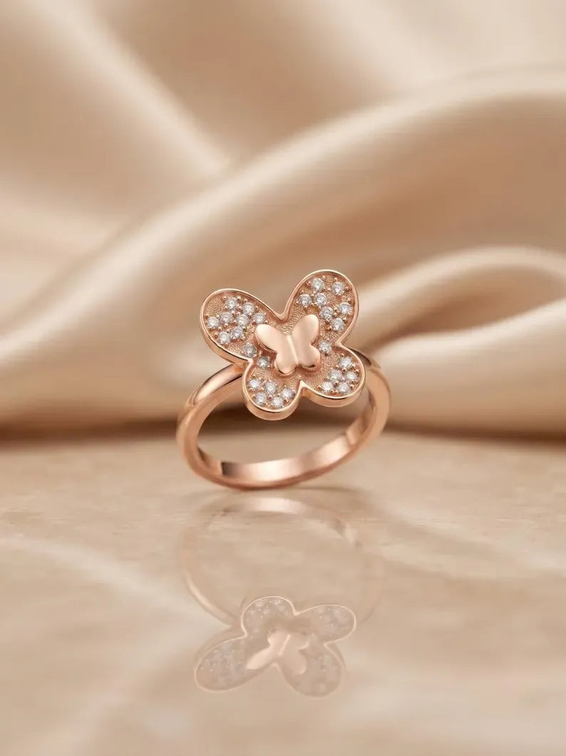 Rose gold butterfly ring styled on satin fabric background