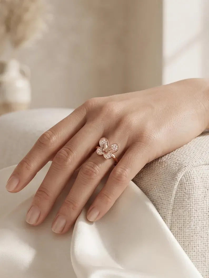 Hand resting on linen chair wearing rose gold butterfly ring