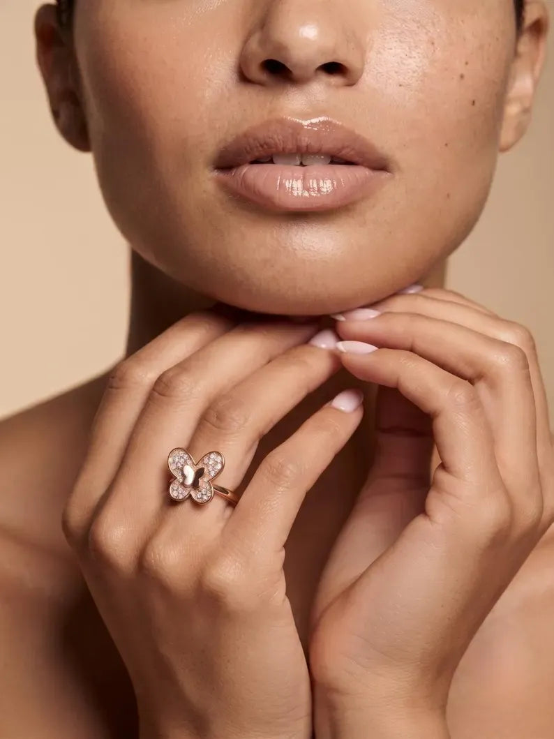 Woman's hand near chin wearing rose gold butterfly pave ring