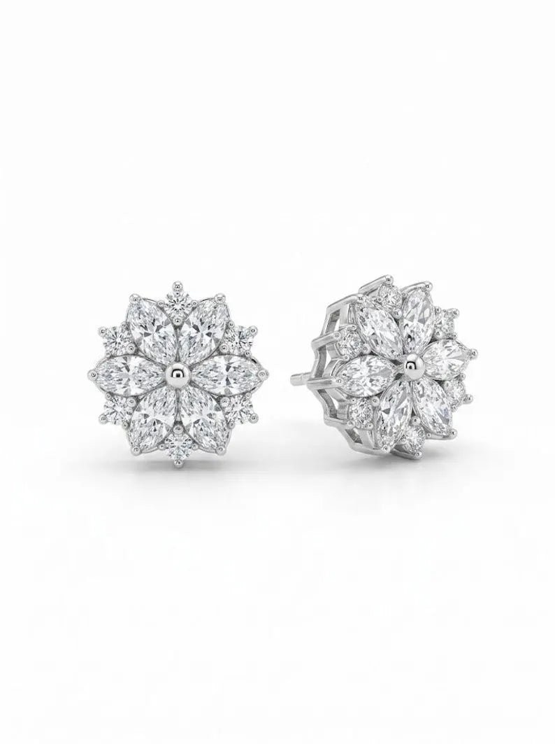 A pair of silver-toned stud earrings featuring a multi-layered snowflake or flower cluster design set with clear gemstones, shown on a plain white background.