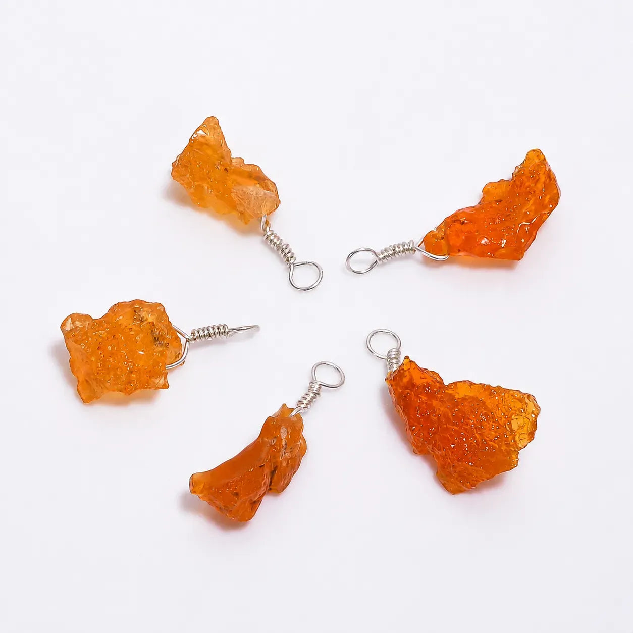Four orange crystal-like earrings on a white background