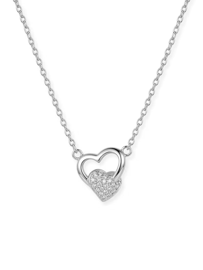 A silver-toned necklace featuring a double-heart pendant, with one heart in polished metal and the other encrusted with small clear stones, displayed on a clean white background.