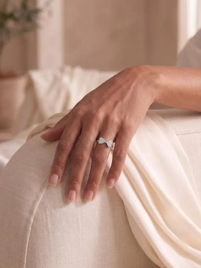 Hand resting on linen fabric wearing double heart CZ ring