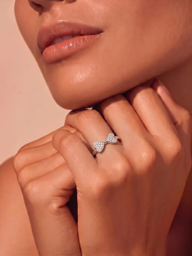 Woman's hand near chin wearing sterling silver double heart pave ring