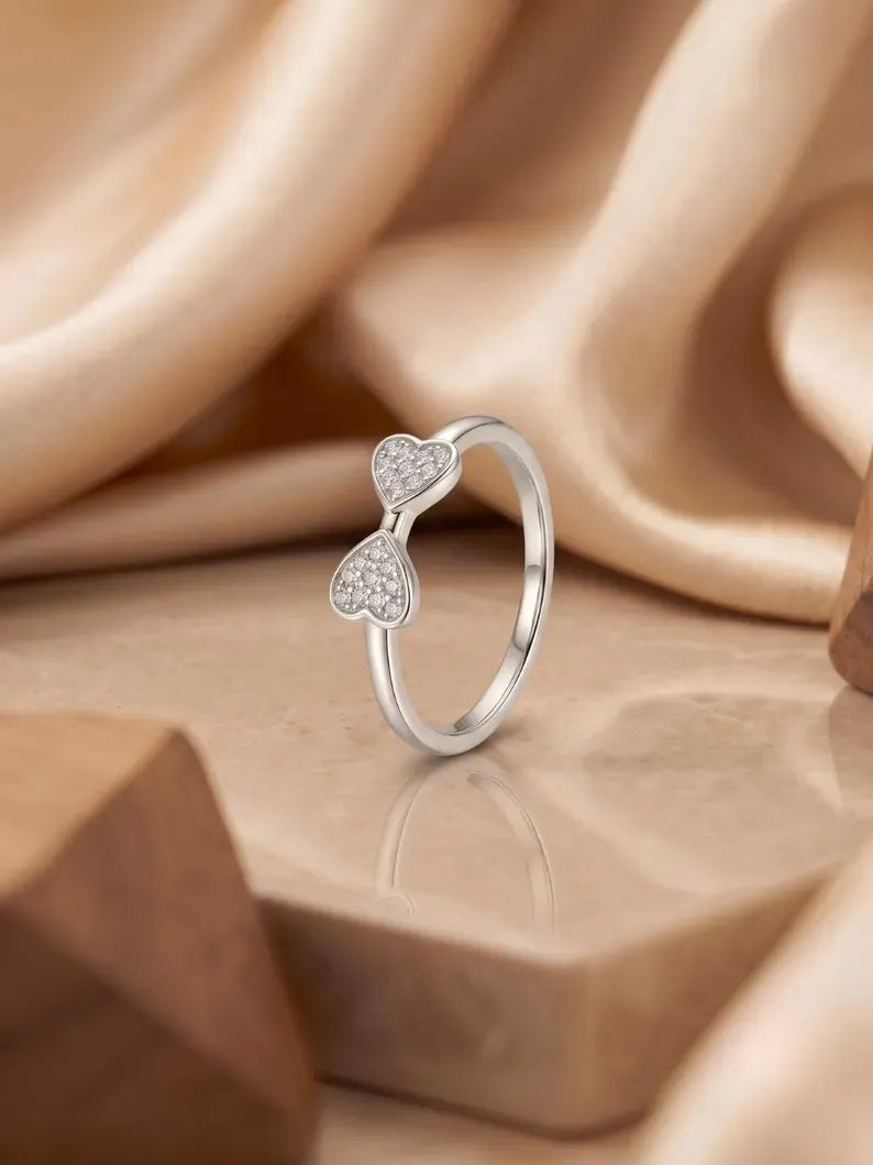 Double heart ring styled on stone surface with wooden decor props