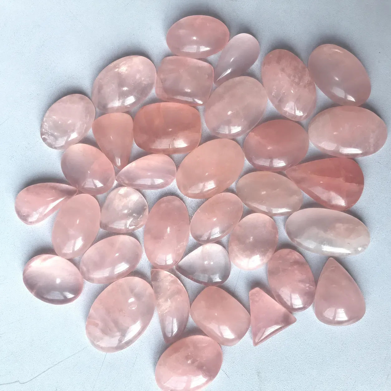 Collection of pink teardrop-shaped stones on a light blue background