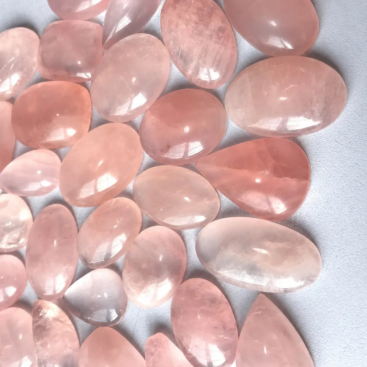 Pink rose quartz stones on a light gray background
