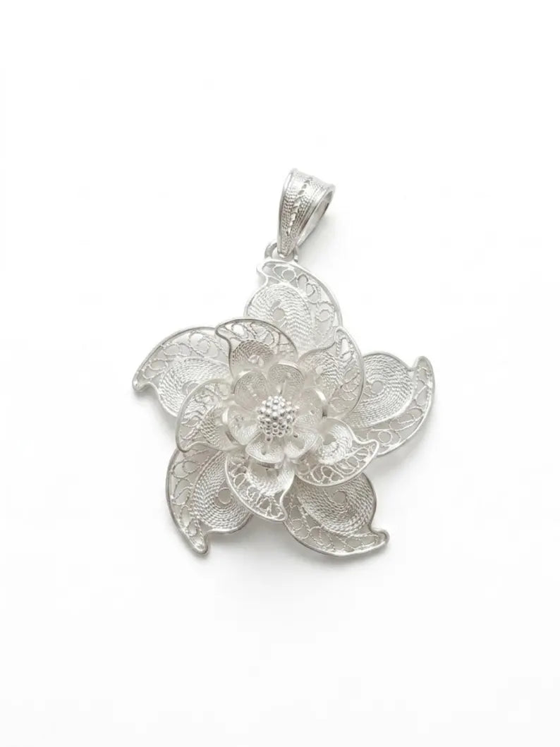 A silver-toned filigree flower pendant on a plain white background.