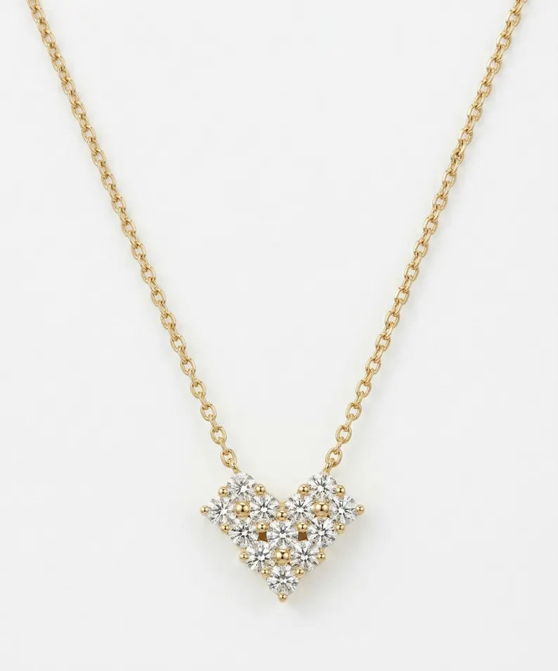 A delicate gold chain necklace featuring a heart-shaped pendant composed of clear gemstones in a silver-toned setting with small gold accents, displayed against a clean white background.