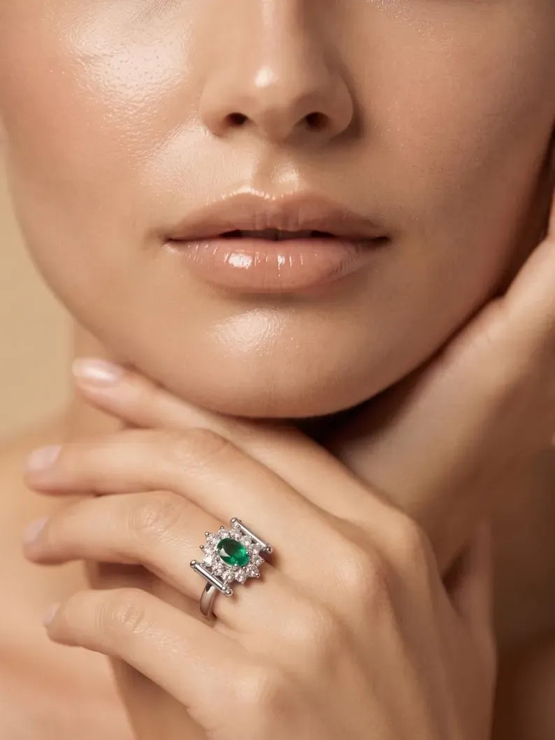 Woman's hand near face wearing oval green gemstone halo ring