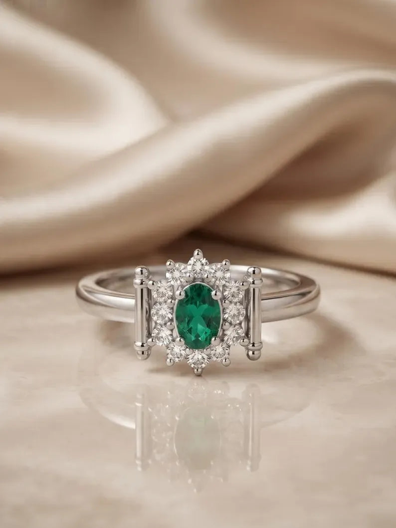 Green gemstone halo ring styled on satin fabric with marble surface
