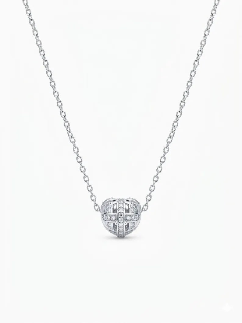 A silver chain necklace with a small, round, diamond-paved pendant featuring a cross-like geometric design, shown against a plain white background.