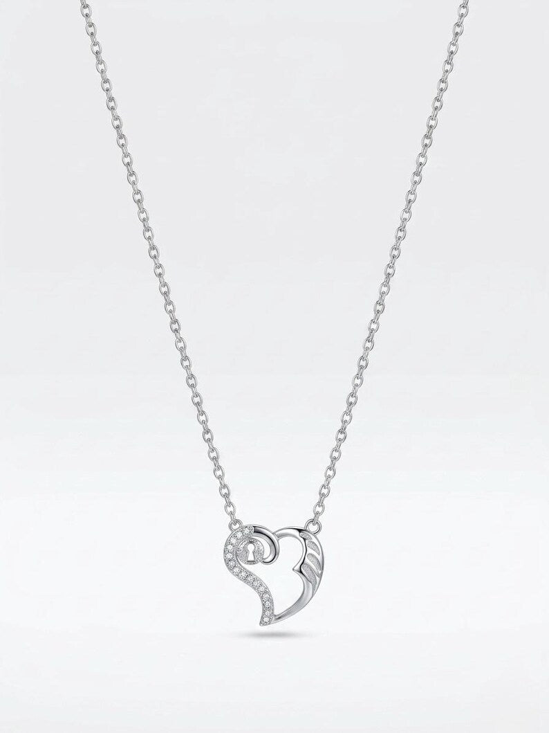 A silver heart-shaped pendant necklace with a pavé-set diamond accent on a delicate silver chain, shown against a light gray gradient background.