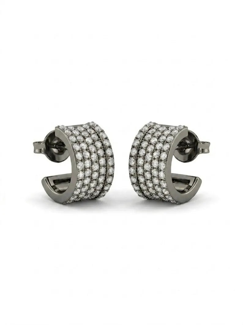 A pair of silver-toned huggie hoop earrings paved with small clear stones, shown against a plain white background.