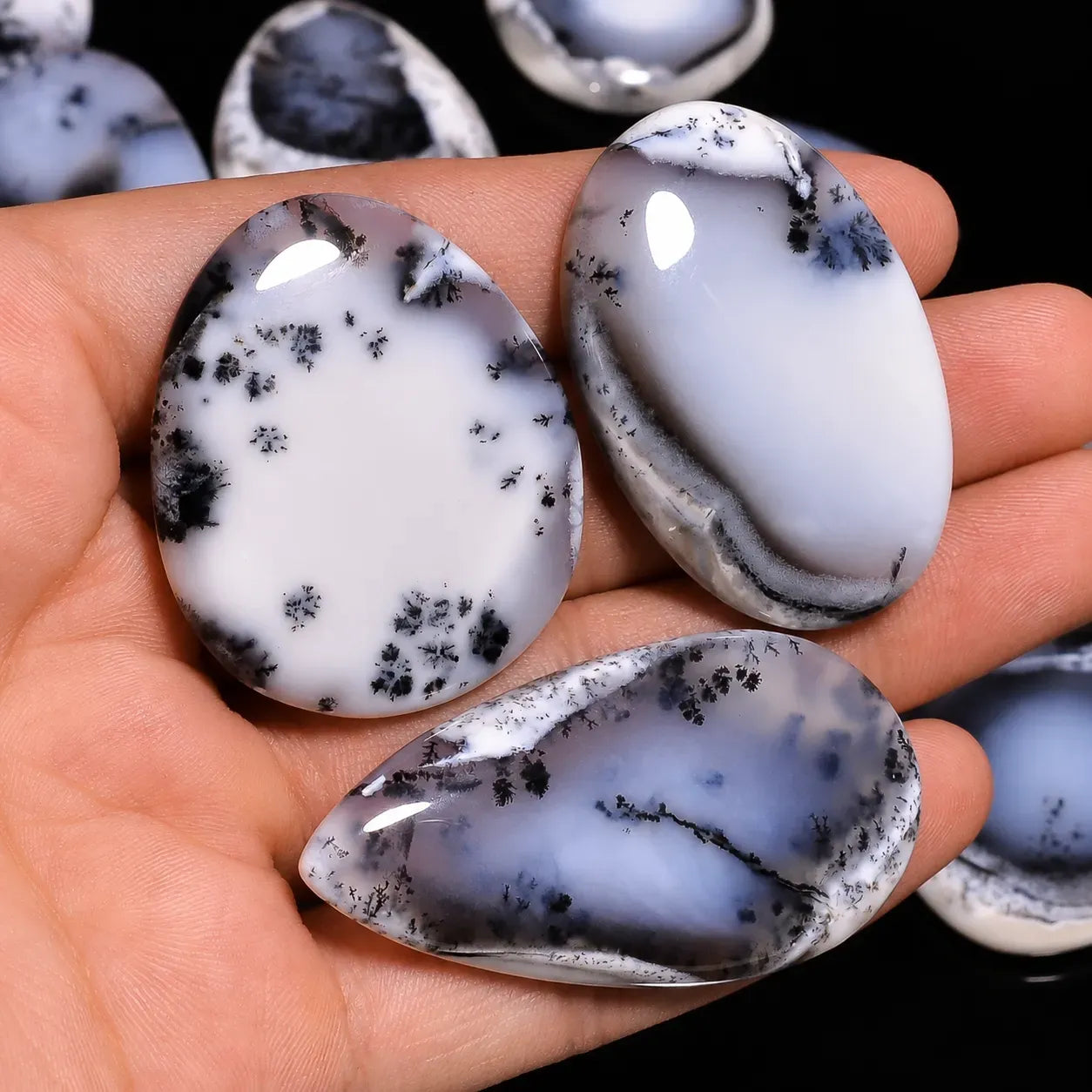 Three oval-shaped marbled stones held in a hand with a blurred background