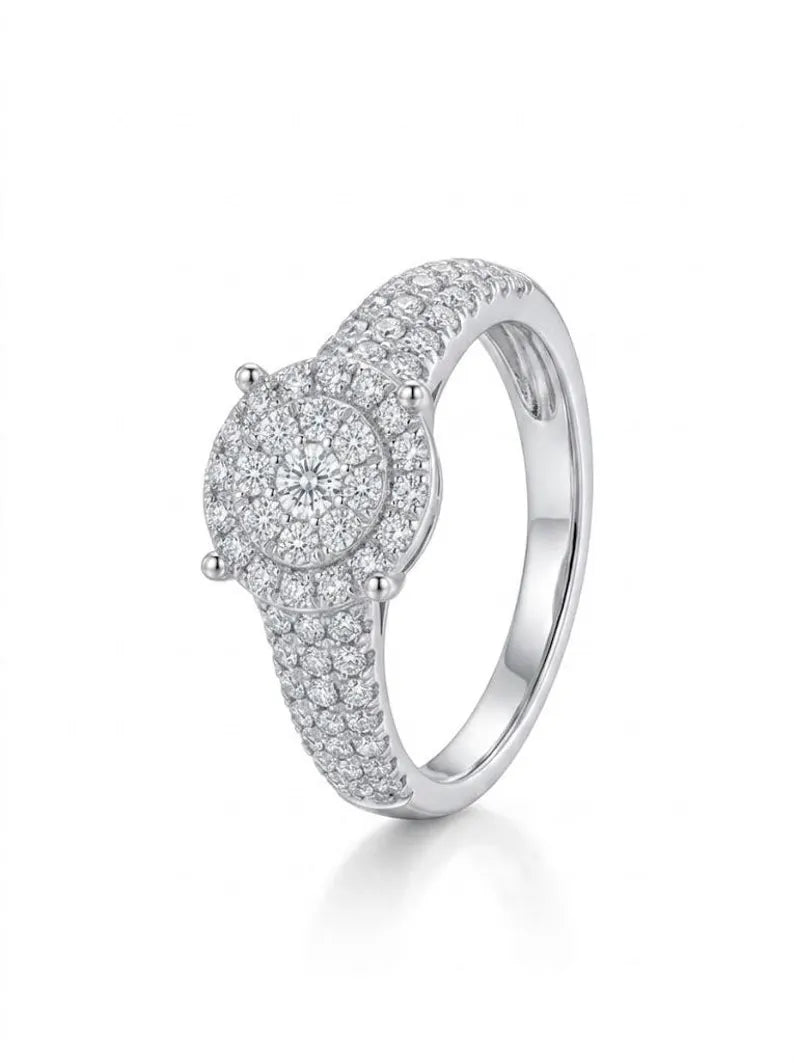 A silver-toned diamond ring with a round pavé halo and a smaller center stone, set on a clean white background with a soft reflection.