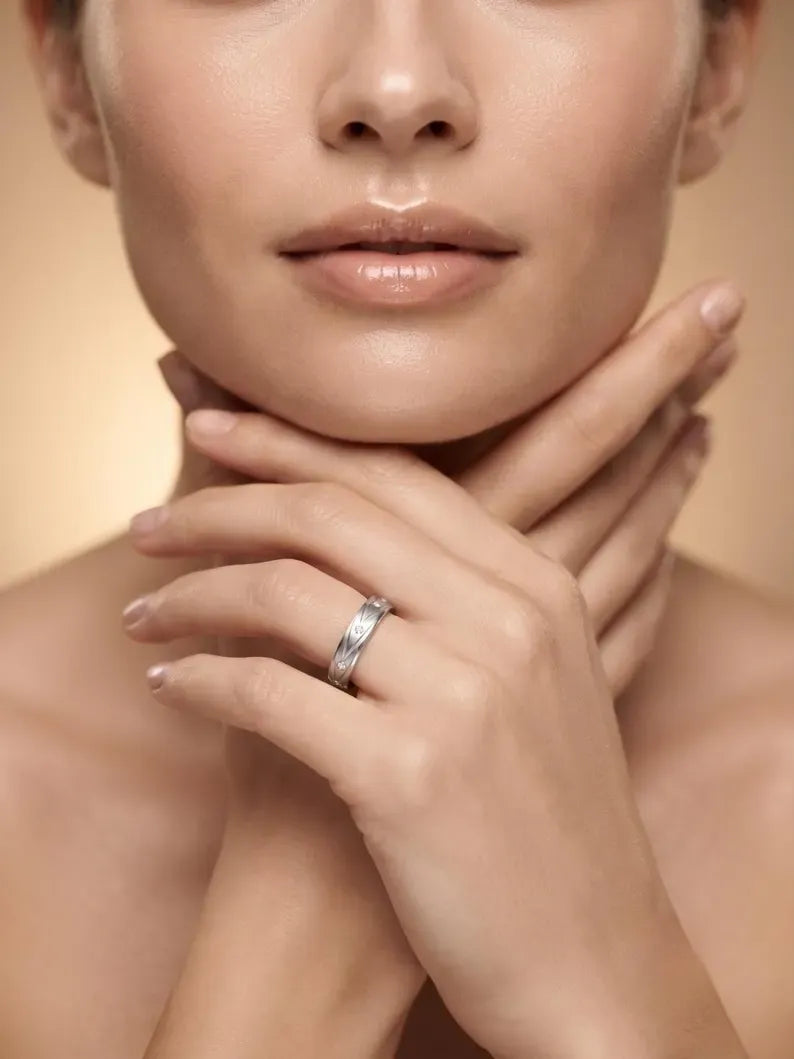 Woman wearing minimalist sterling silver wedding band with brushed finish on hand