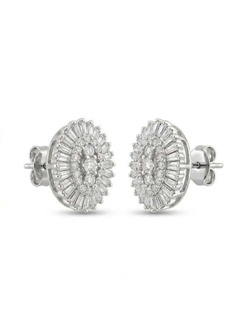 A pair of round cluster stud earrings in silver-toned metal, featuring multiple rows of clear baguette and round-cut stones, Oval halo statement stud earring worn on ear, sunburst, shown against a plain white background.