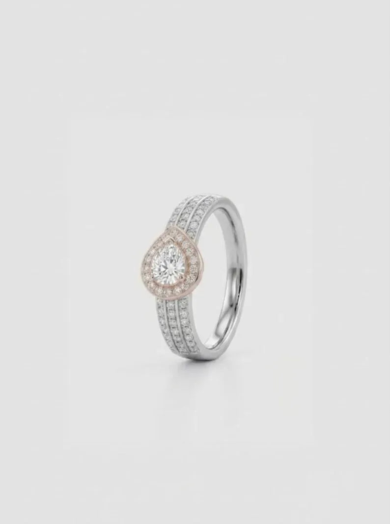 Side angle view of sterling silver pear halo engagement ring with rose gold accent and pave band