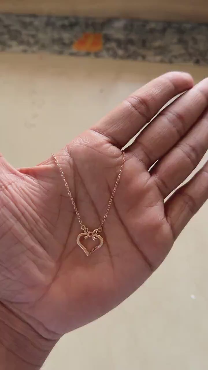 Close-up of zircon detail on rose gold bow heart pendant