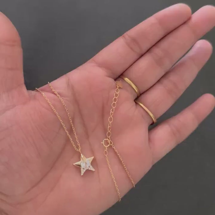 Rose gold star pendant necklace held in hand showing pendant and clasp