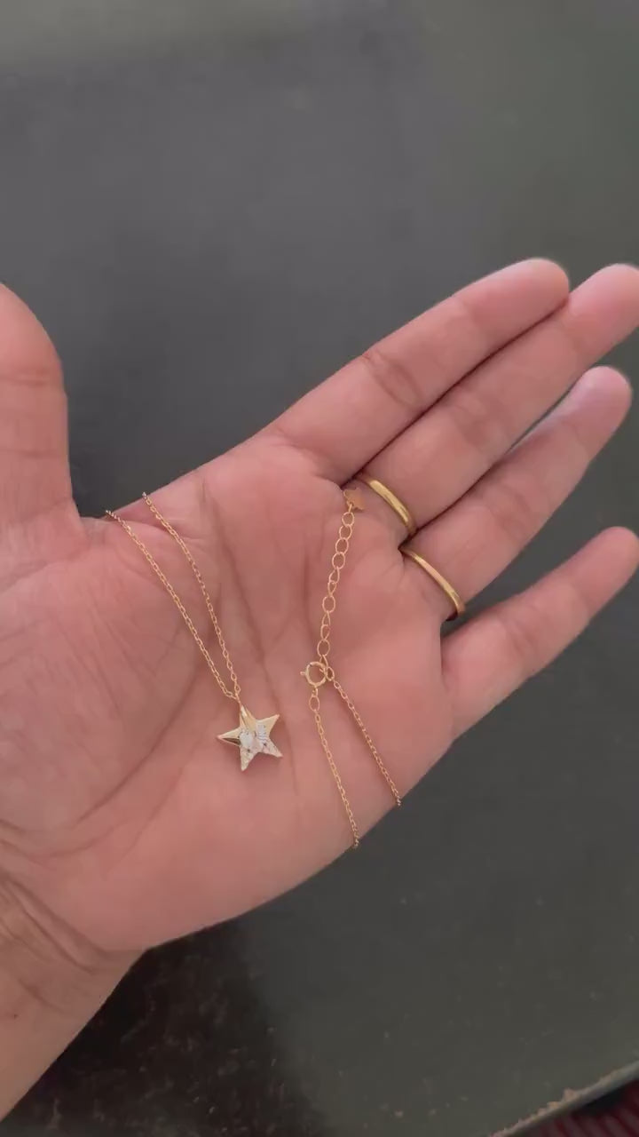 Rose gold star pendant necklace held in hand showing pendant and clasp