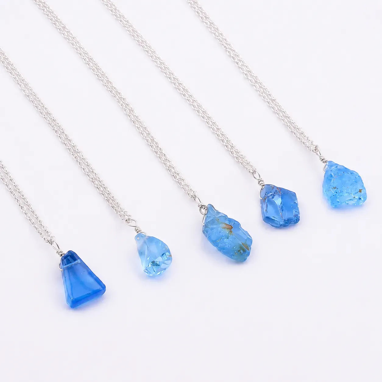 Three blue pendant necklaces on a white background