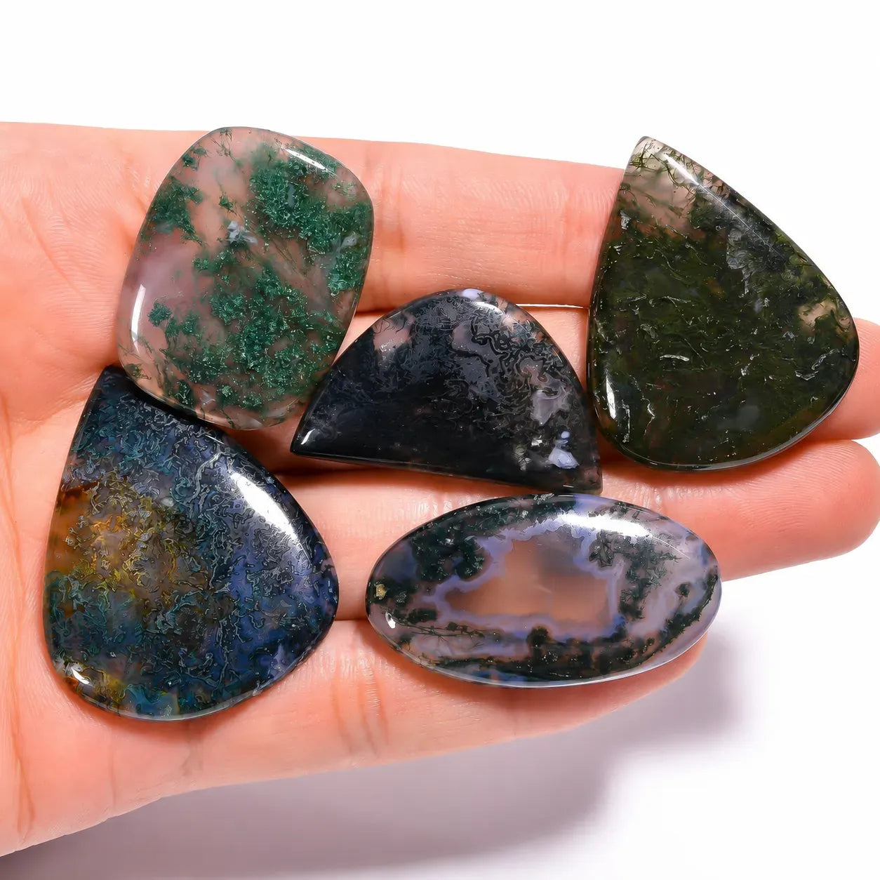 Five teardrop-shaped gemstones held in a hand on a white background