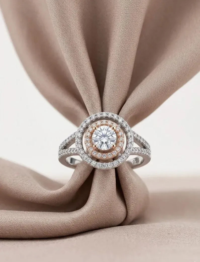 Close up of sterling silver bridal ring with rose gold inner halo and round cubic zirconia center stone