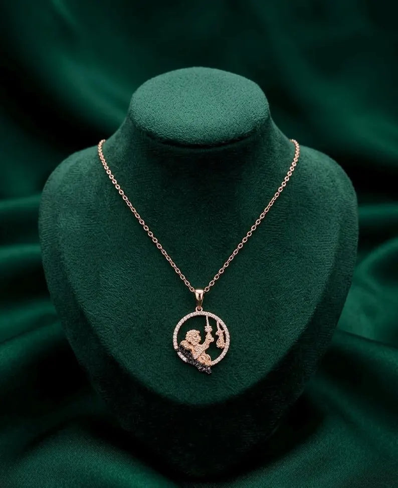 A rose gold pendant necklace featuring a circular design with a central figure and small sparkling stones, displayed on a dark green velvet jewelry bust.