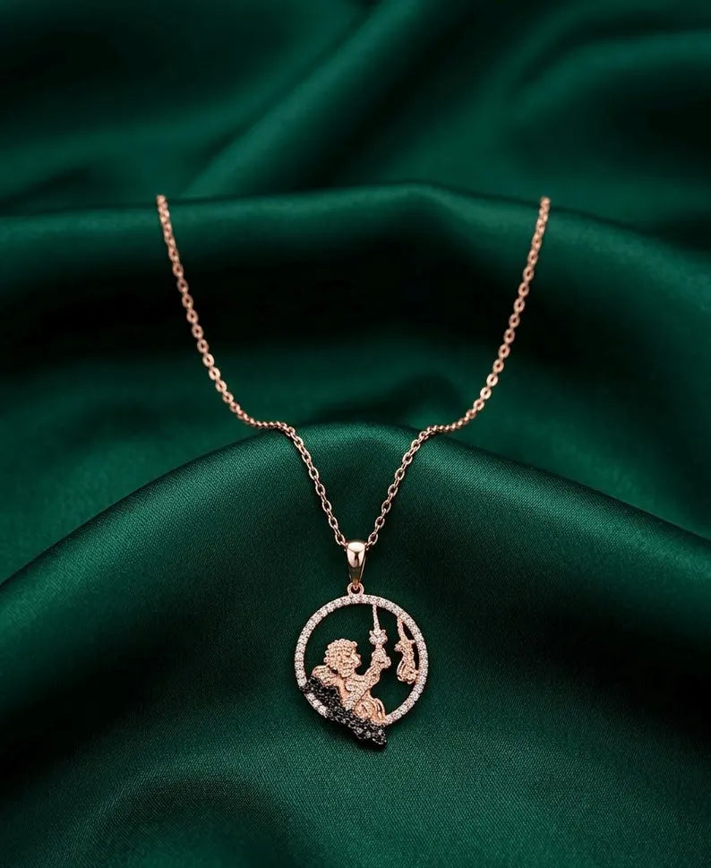 A rose gold necklace with a circular pendant featuring a cherub design, displayed on draped dark green satin fabric.