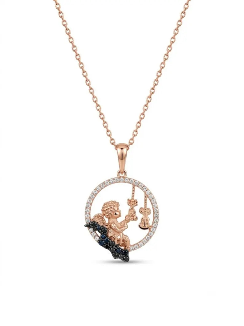 A rose gold pendant necklace featuring a cherub holding a scale of justice, set against a circular halo of small clear stones and resting on a dark blue wave detail, shown on a white background.