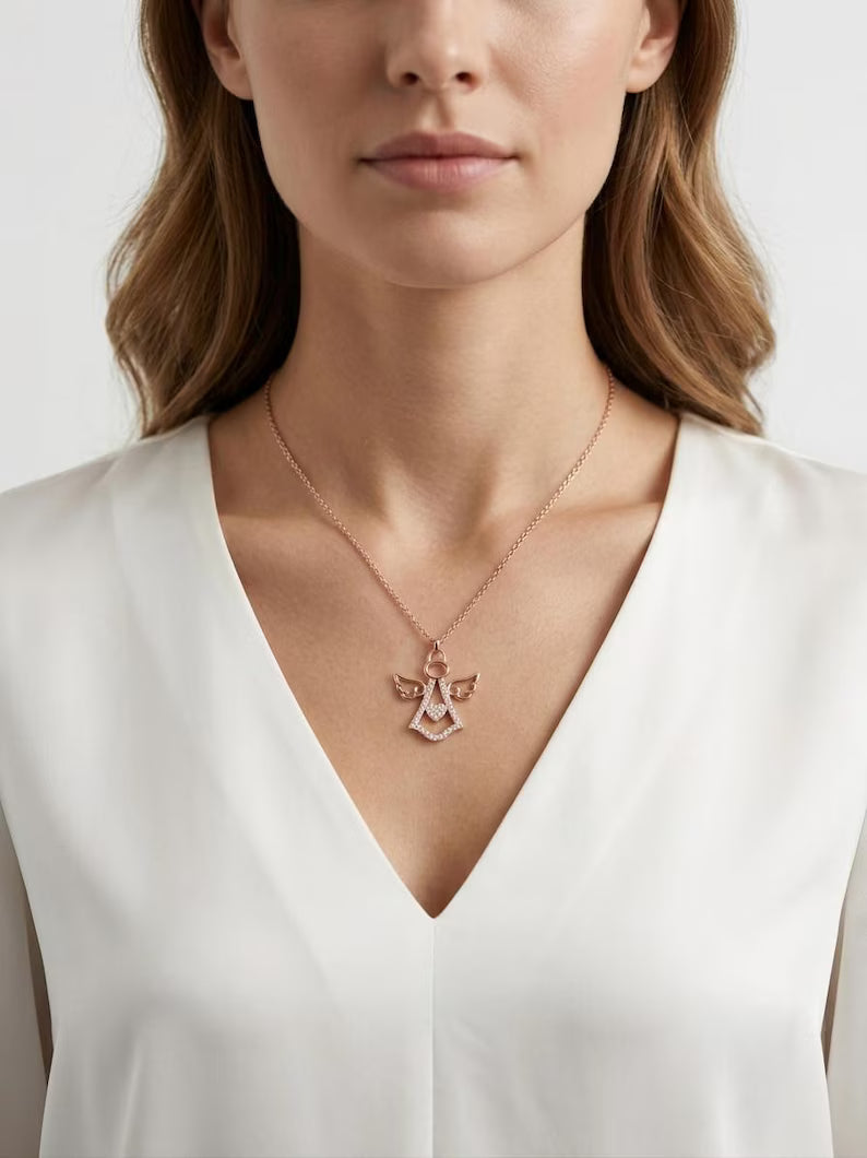 A close-up of a woman wearing a delicate rose gold angel pendant necklace on a fine chain, paired with a white V-neck top.