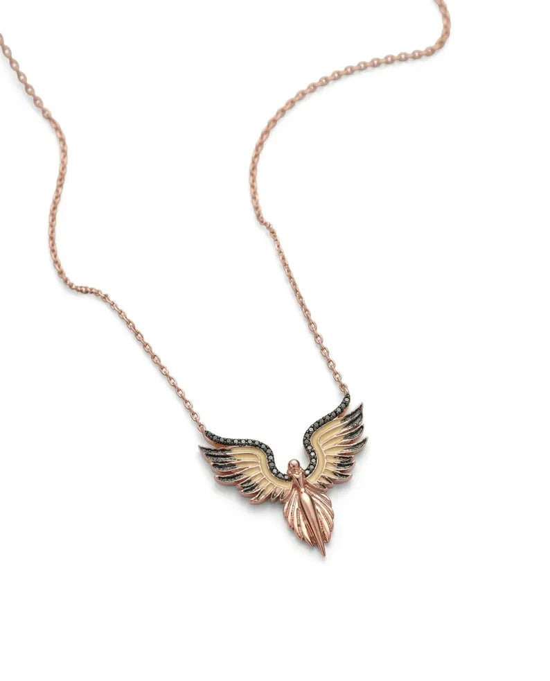 A rose gold angel wing pendant necklace with black and gold accents, displayed on a clean white background.