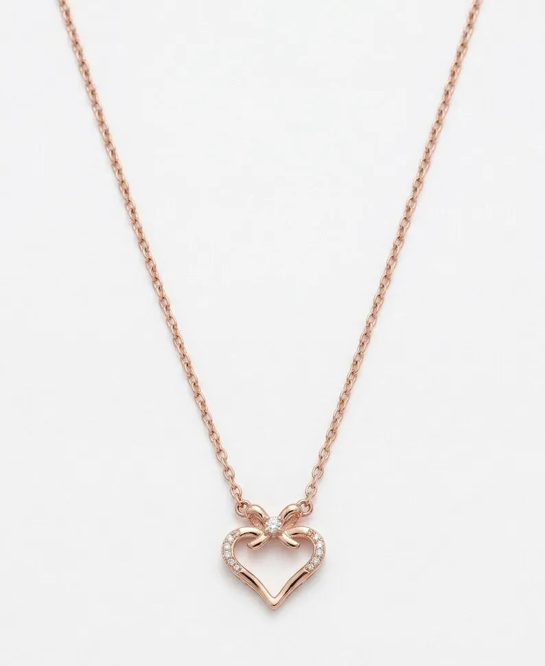 A delicate rose gold chain necklace featuring a small open heart pendant with tiny clear stones along the top curve, displayed against a clean white background.
