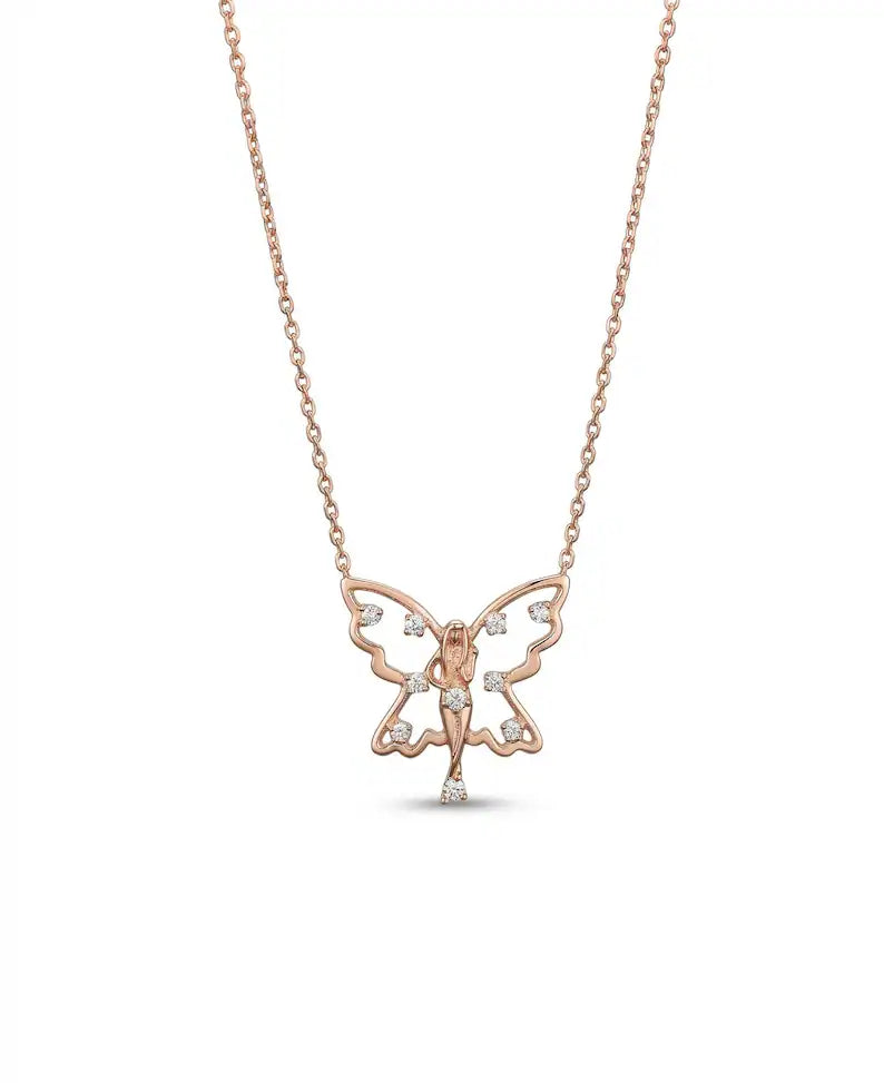 A delicate rose gold butterfly pendant necklace with a small fairy figure in the center, accented with tiny clear stones, shown on a clean white background.