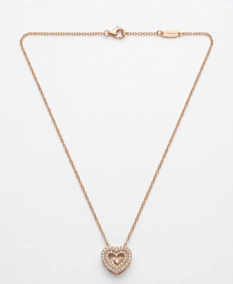 A delicate rose gold chain necklace with a small heart-shaped pendant paved with clear stones, displayed on a clean white background.