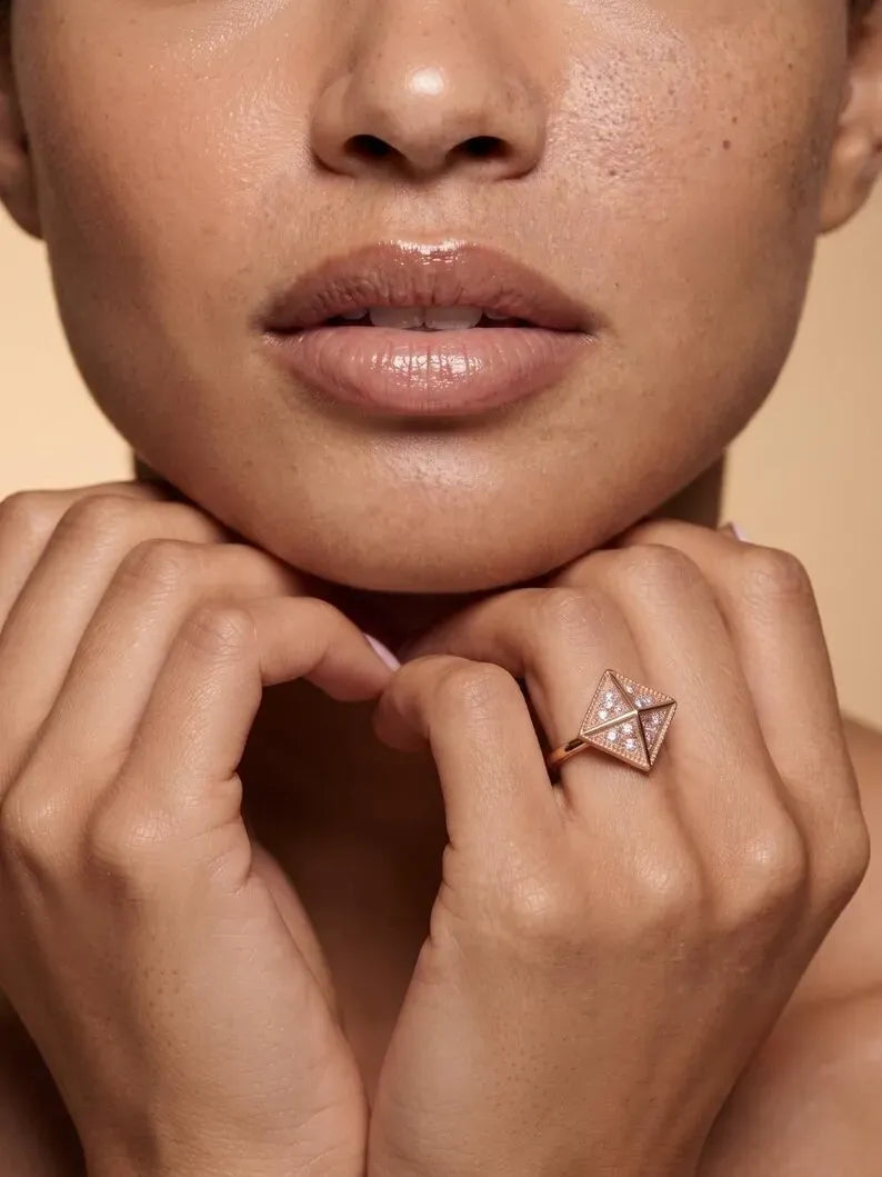 Woman wearing rose gold geometric pyramid ring with pave crystal detailing near face