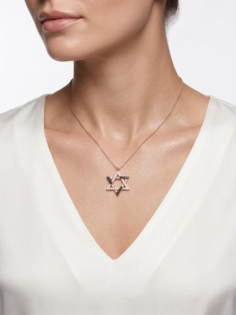 A close-up of a model wearing a delicate rose gold chain necklace with a Star of David pendant embellished with small sparkling crystals.