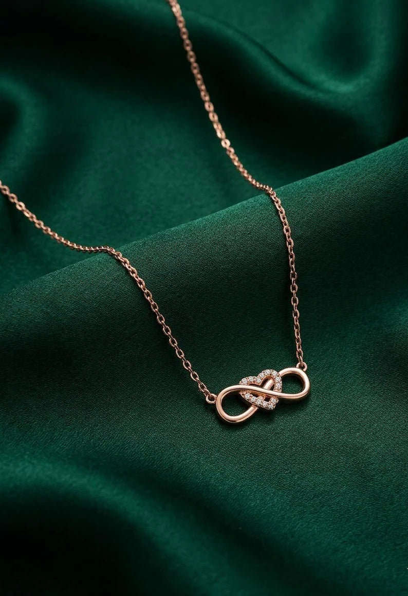 Infinity heart necklace on dark green satin backdrop