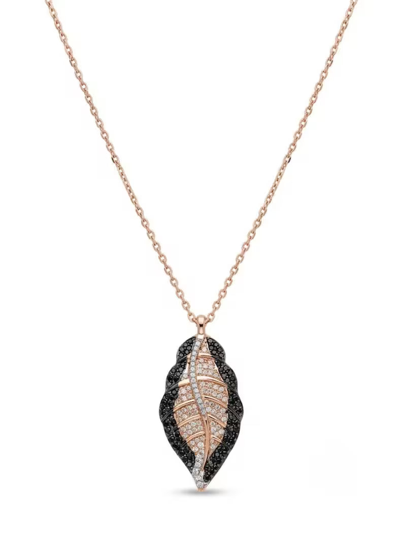 A delicate rose gold chain necklace featuring a leaf-shaped pendant. The pendant is detailed with a central rose gold and white stone pattern, surrounded by a textured black stone border, set against a plain white background.