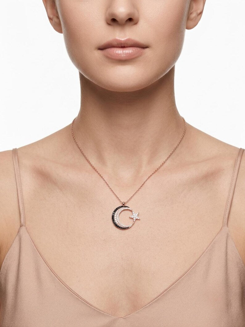 A close-up of a model wearing a delicate rose gold necklace with a crescent moon and star pendant, set against a clean white background.
