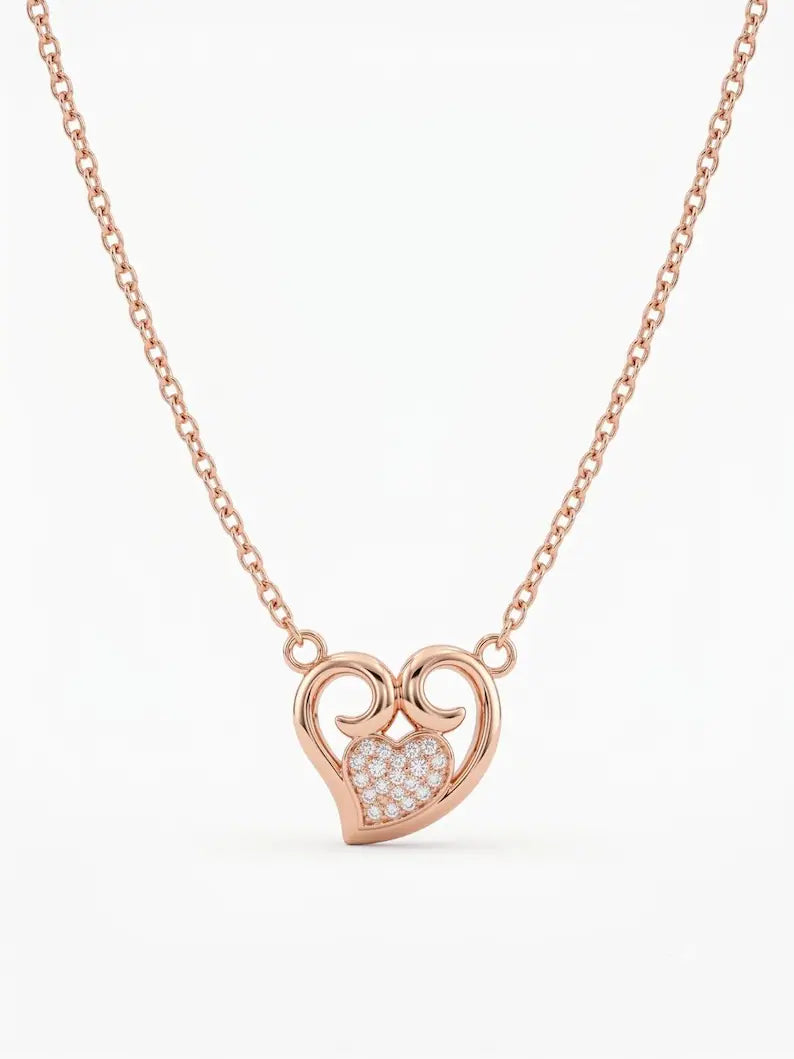 A rose gold necklace with a heart-shaped pendant featuring a pavé-set clear stone heart in the center, shown against a plain white background.